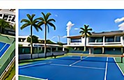 Cancha de tenis frente a edificio de resort con palmeras.