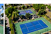 Vista aérea de cancha de tenis en zona hotelera con palmeras.